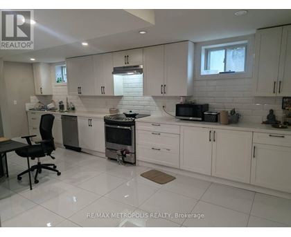 A white kitchen with a black chair and a window.