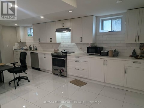 A white kitchen with a black chair and a window.
