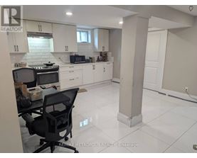 A kitchen with white cabinets and a black chair.
