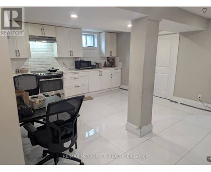A kitchen with white cabinets and a black chair.