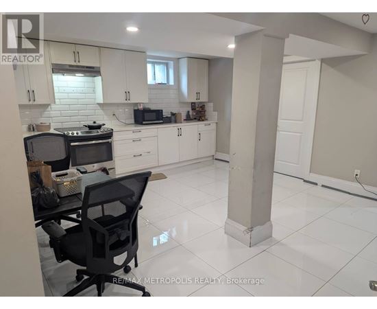 A kitchen with white cabinets and a black chair.
