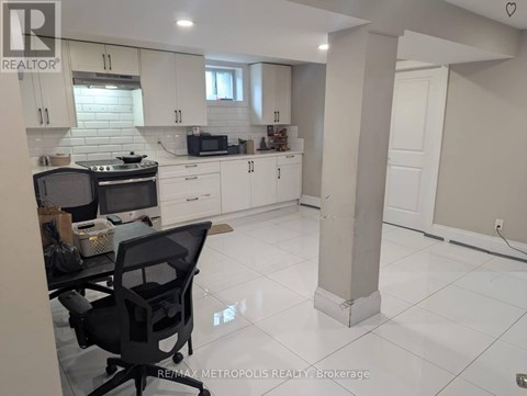 A kitchen with white cabinets and a black chair.
