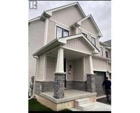 A house with a grey and white exterior and a stone pillar on the front porch.