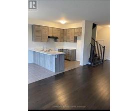 A modern kitchen with wooden cabinets and a black staircase.