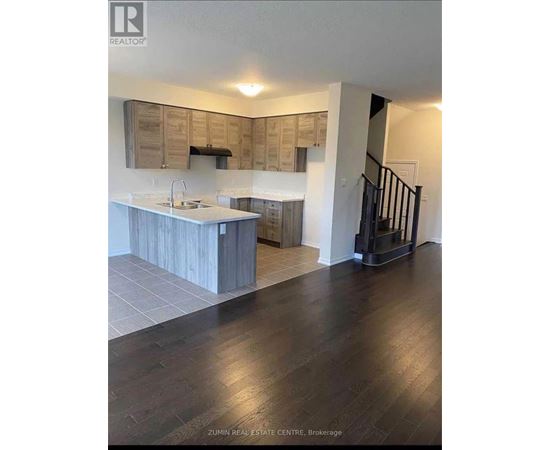 A modern kitchen with wooden cabinets and a black staircase.