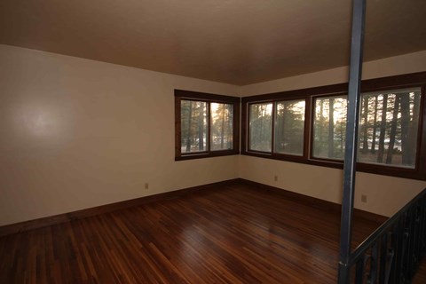A room with wooden floors and a window with a view of trees.