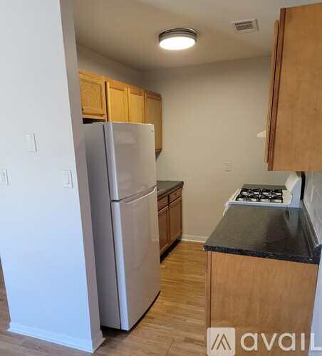 A kitchen with a refrigerator, stove, and cabinets.