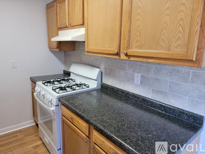 A kitchen with a white stove and wooden cabinets.