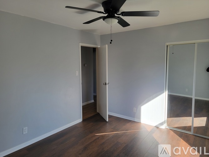 A room with a ceiling fan and a door leading to another room.