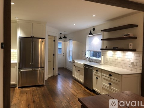 A kitchen with a stainless steel refrigerator and wooden floors.
