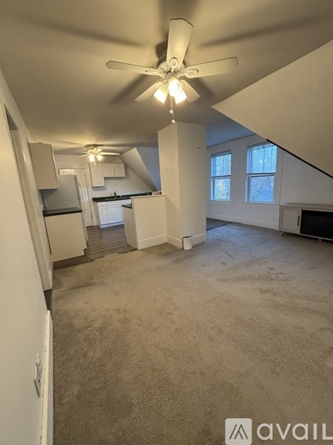 A spacious room with a ceiling fan and carpeted floor.