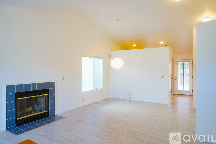 A spacious living room with a fireplace and a large window.