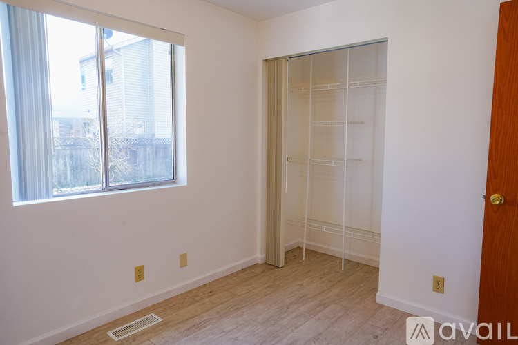 A room with a white wall and a window with a view of a building outside.