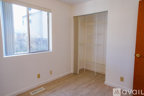 A room with a white wall and a window with a view of a building outside.