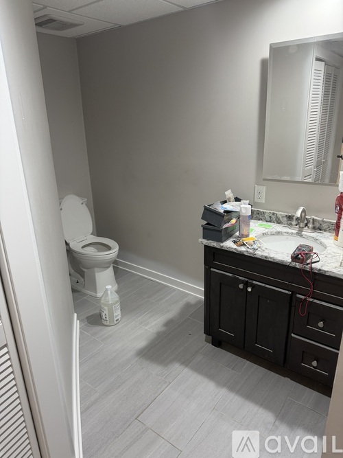 A bathroom with a toilet, sink, and mirror.