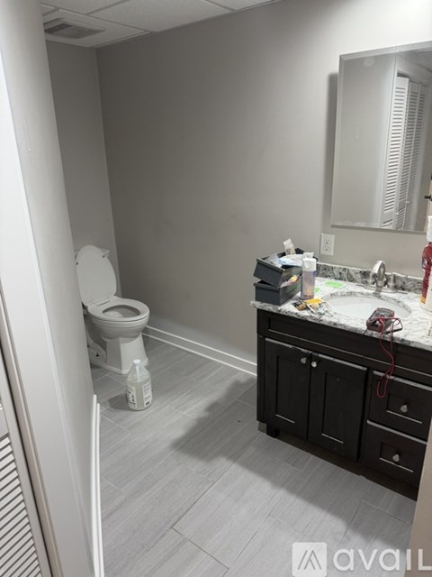 A bathroom with a toilet, sink, and mirror.