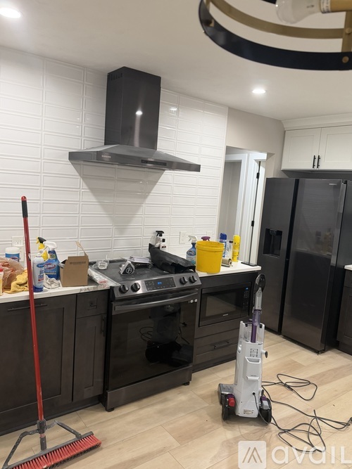 A kitchen with black appliances and a red broom.