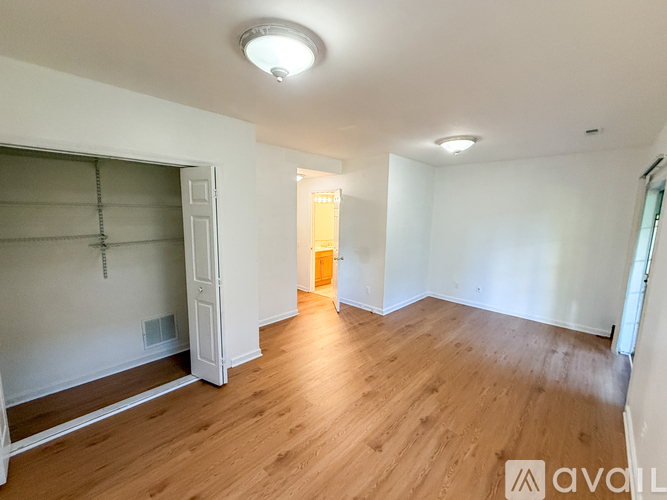 A room with wooden floors and white walls, with a door at the end of the room.
