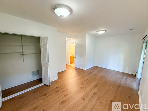 A room with wooden floors and white walls, with a door at the end of the room.