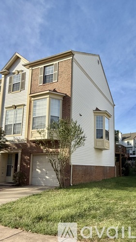 A two-story house with a garage and a tree in front.