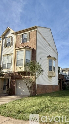 A two-story house with a garage and a tree in front.