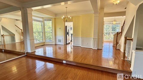 A spacious living room with hardwood floors and a staircase on the left side.