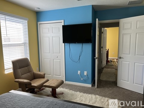 A bedroom with a blue wall and a flat screen TV mounted on it.