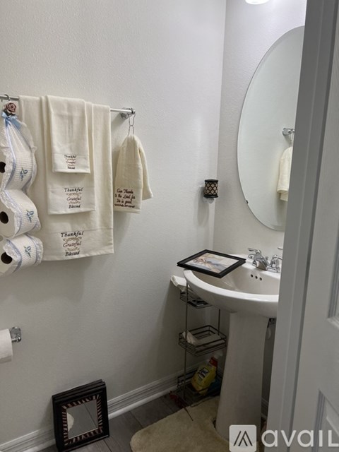 A bathroom with a white sink and towels hanging on the wall.