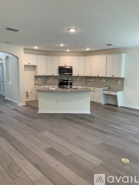 A kitchen with a wooden floor and white cabinets.