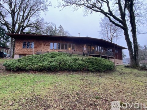 A wooden house with a curved roof and a green bush in front.