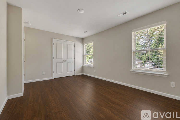 A room with wooden floors and a window showing trees outside.