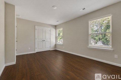 A room with wooden floors and a window showing trees outside.