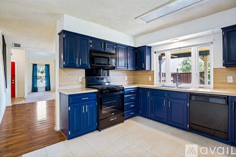 A kitchen with blue cabinets and black appliances.