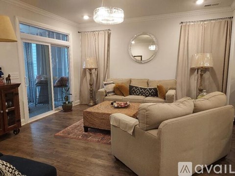 A living room with a beige sofa, a round mirror, and a chandelier.