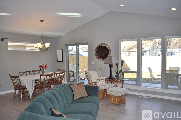 A living room with a green couch and a dining table with chairs.