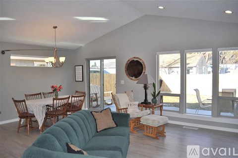 A living room with a green couch and a dining table with chairs.