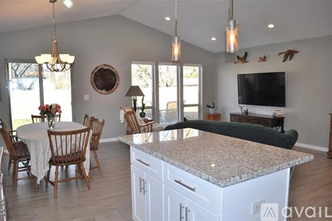 A kitchen with a table and chairs and a TV mounted on the wall.