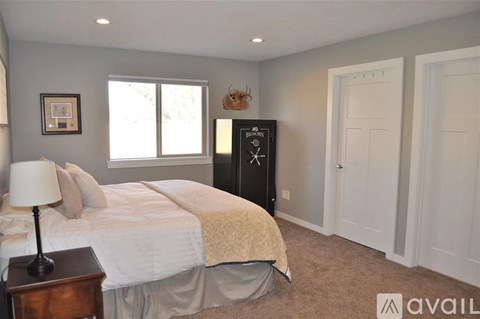 A bedroom with a bed, nightstand, and a window.