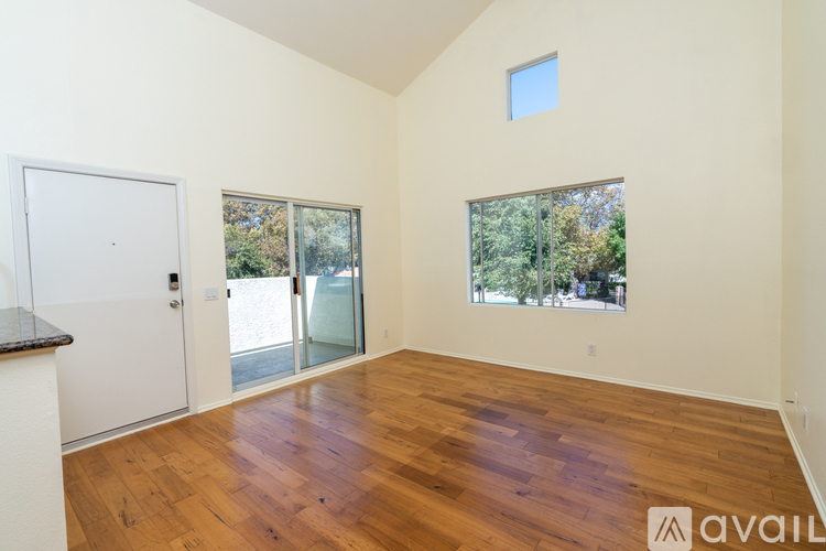 A room with wooden floors and a window overlooking trees.