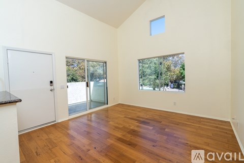 A room with wooden floors and a window overlooking trees.