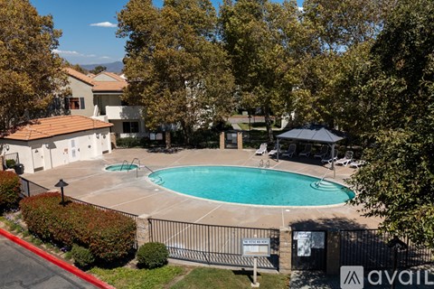 A pool surrounded by a fence and trees.