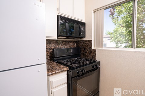 A kitchen with a black stove and microwave above a black countertop.