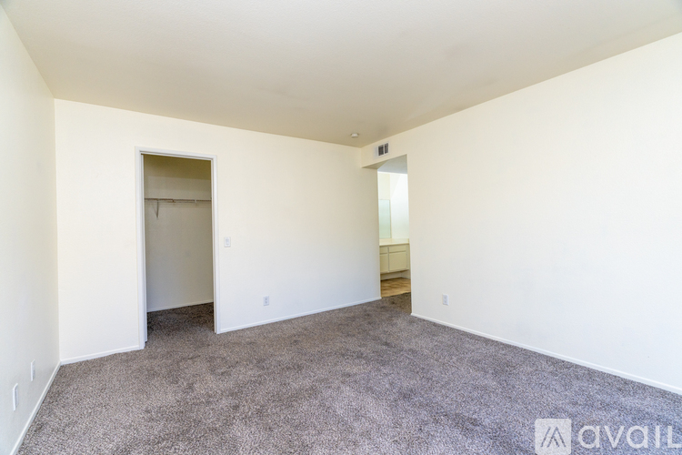 A spacious room with a carpeted floor and white walls.