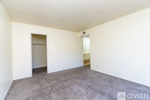 A spacious room with a carpeted floor and white walls.