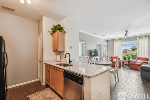 A kitchen with a refrigerator, sink, and a dining area with chairs and a table.