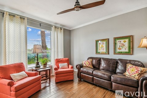 A living room with a brown leather couch and red cushions.