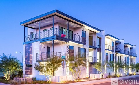 A modern multi-story building with balconies and lights on.