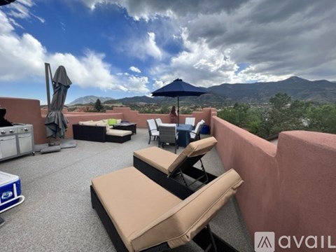 A patio with two chairs and an umbrella overlooking a mountain range.