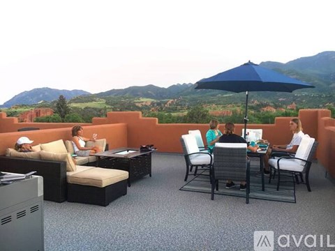 A group of people are sitting around a table on a balcony with a mountain view.