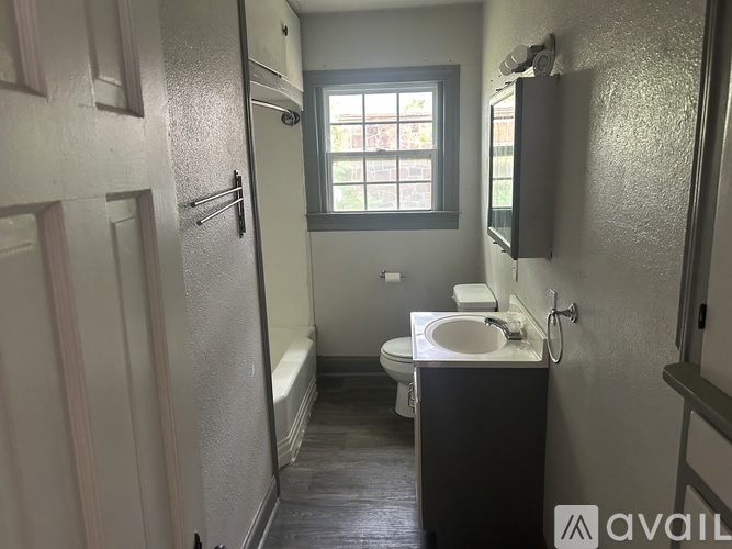 A bathroom with a toilet, sink, and window.